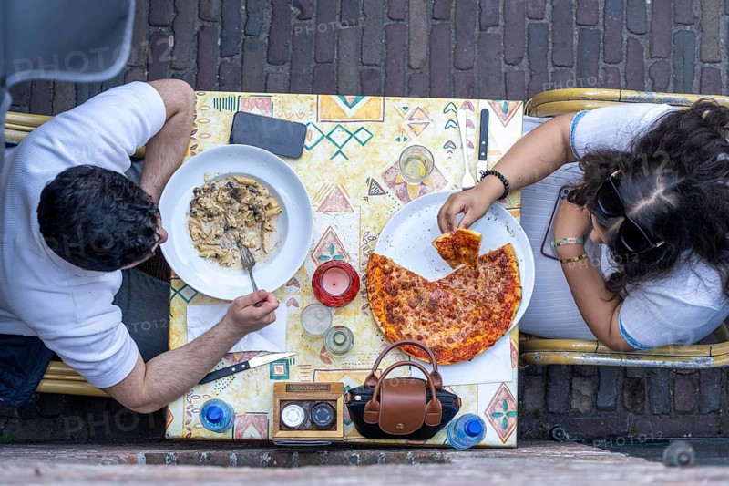 Man and woman sitting in an Italian restaurant eating pizza and pasta, symbolic picture