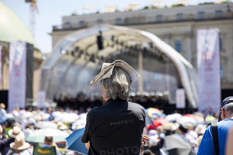 A visitor protects himself from the sun with a newspaper on his head at the Staatsoper für alle, a free open-air concert with conductor Christian Thielemann and the Staatskapelle Berlin on Berlin's Bebelplatz, Berlin, 22 June 2025