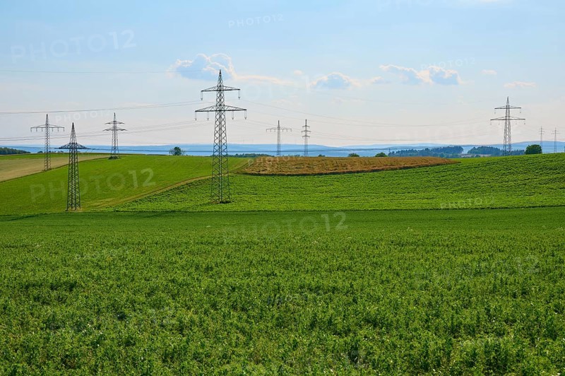 Extensive green fields with electricity pylons and a blue sky with clouds, Marktheidenfeld, Bavaria, Germany