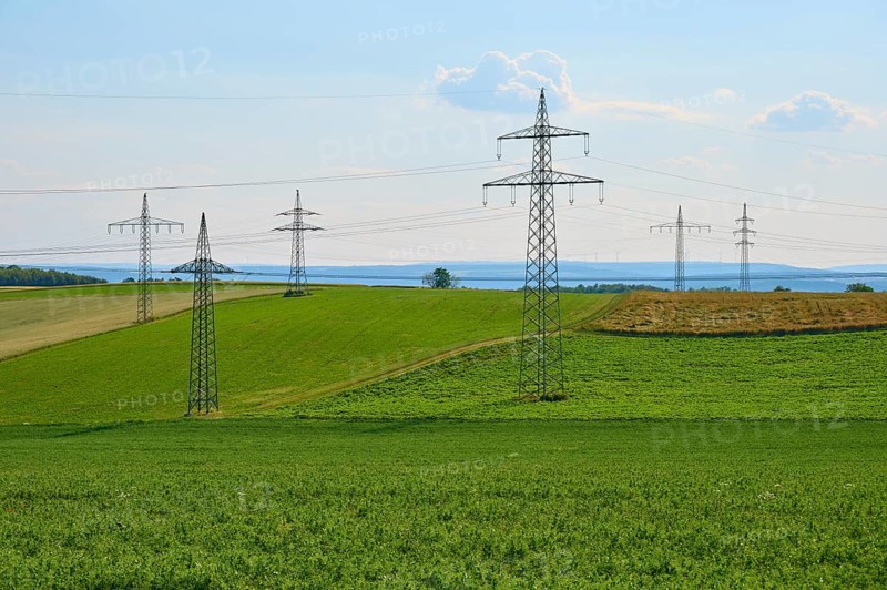 Green fields with a row of electricity pylons under a blue sky, Marktheidenfeld, Bavaria, Germany
