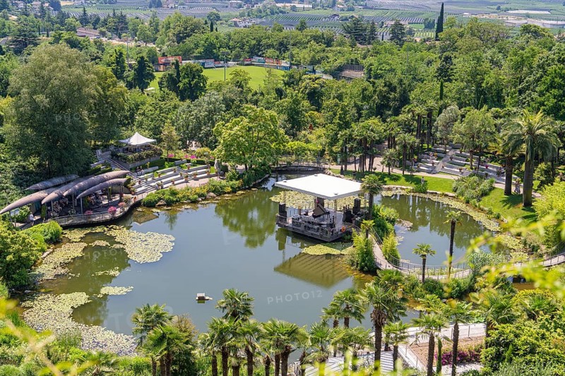 A pond with a pavilion in the middle of a green park, surrounded by landscape, Botanical Garden, The Gardens of Trauttmansdorff Castle, Merano, South Tyrol, Italy