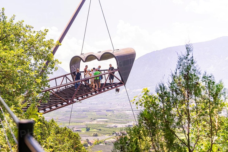 Tourists on a floating viewing platform with a mountain landscape in the background, Botanical Gardens, The Gardens of Trauttmansdorff Castle, Merano, South Tyrol, Italy