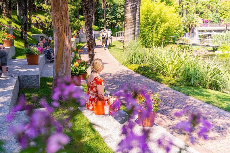 People relaxing in a sunny park with flowers and green grass, Botanical Garden, The Gardens of Trauttmansdorff Castle, Merano, South Tyrol, Italy