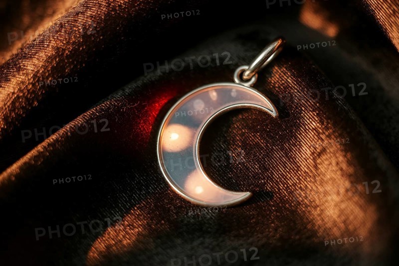 Silver crescent moon pendant on velvet, symbol of witchcraft and lunar magic. Generative ai, AI generated