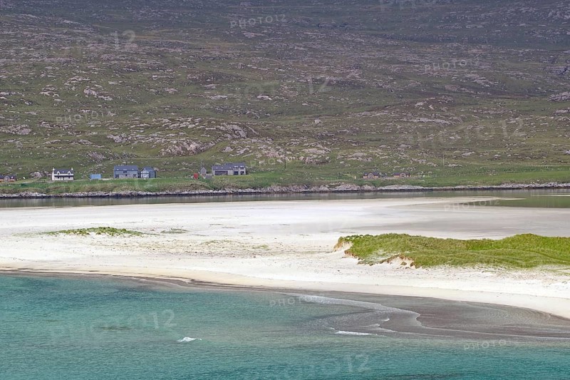 Tranquil coastal landscape with white sand and green land in flat light under a cloudy sky, Seilebost Beach, Isle of Harris, Hebrides, Scotland, United Kingdom