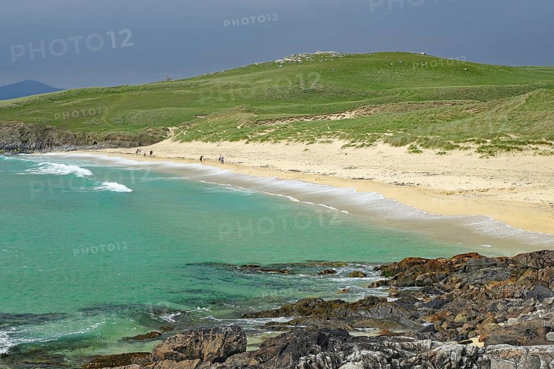 Picturesque coastal landscape with green hill, sandy beach and turquoise sea under a cloudy sky, Isle of Lewis, Hebrides, Scotland, Great Britain