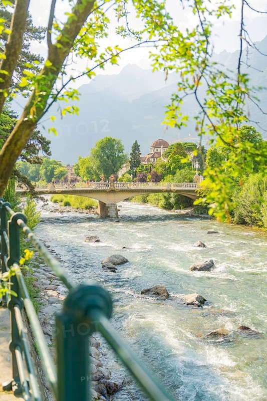Scenic view of a river with bridge and trees in the background, Merano, Italy