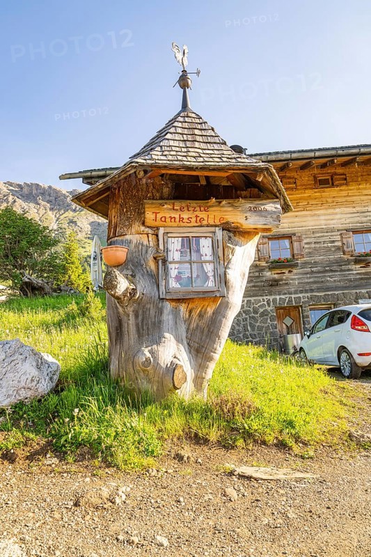 Whimsical wooden petrol station in a rural setting with car and meadow, Alpe di Siusi, Dolomites, South Tyrol, Italy