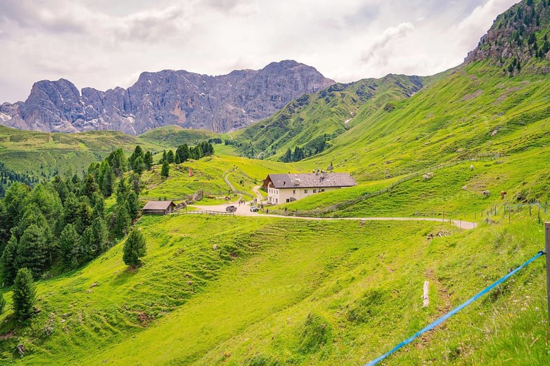 A village with buildings in the middle of a green, hilly mountain landscape, Alpe di Siusi, Dolomites, South Tyrol, Italy