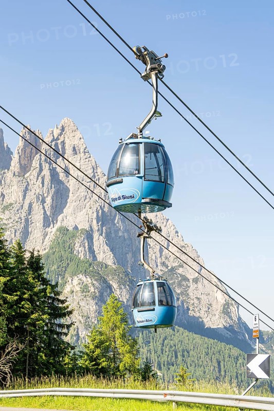 Blue cable car gondolas in front of a rocky mountain backdrop in fine weather, Alpe di Siusi, Dolomites, South Tyrol, Italy