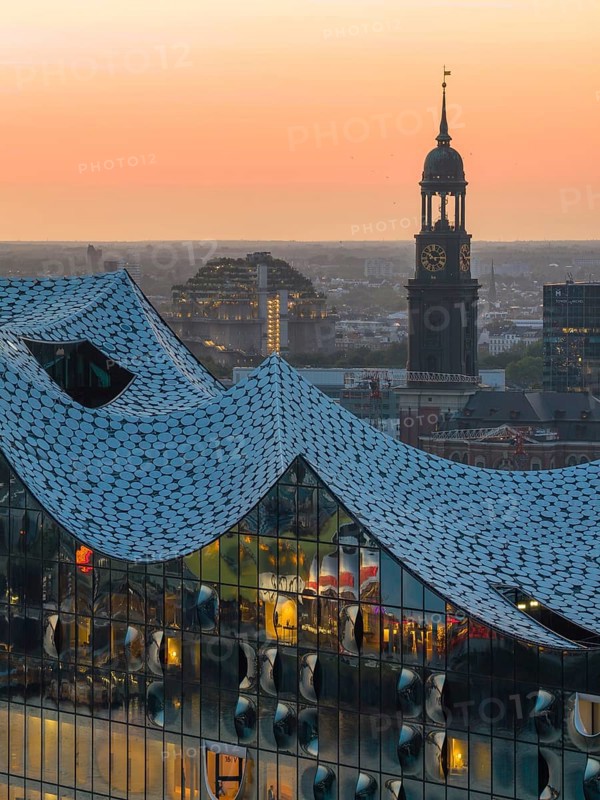 Aerial view of the Elbphilharmonie at sunset with illuminated windows and view over Hamburg and the main church St Michaelis (Michel), Hamburg, Germany