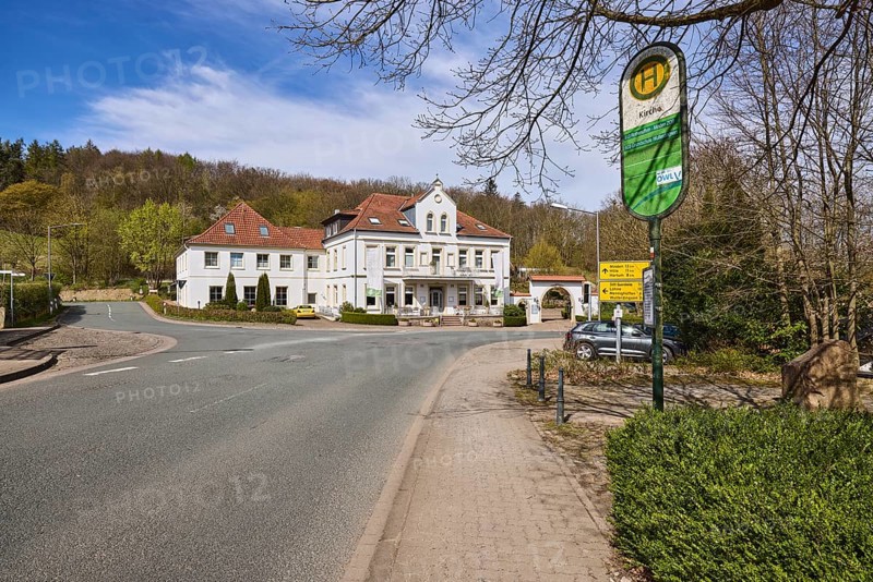 Hotel and restaurant Wittekindsquelle, building, bus stop church, pavement, concrete paving stones, asphalt road, trees, forest, blue sky, cirrostratus clouds, intersection Volmerdingsener Straße with Bergkirchener Straße, Bad Oeynhausen, Mühlenkreis Minden-Lübbecke, North Rhine-Westphalia, Germany