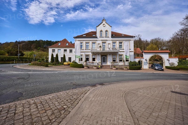 Hotel and restaurant Wittekindsquelle, building, pavement, concrete paving stones, asphalt road, trees, forest, blue sky, cirrostratus clouds, intersection of Volmerdingsener Straße and Bergkirchener Straße, Bad Oeynhausen, Mühlenkreis Minden-Lübbecke, North Rhine-Westphalia, Germany