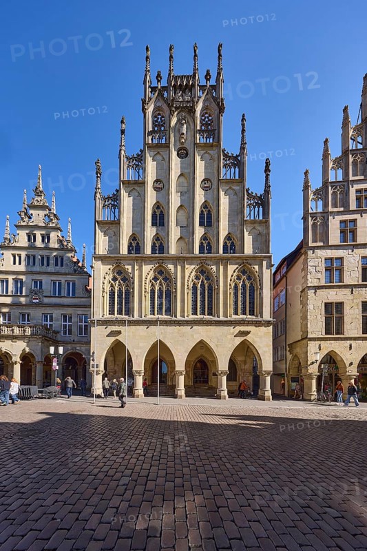 Historic town hall, facade, windows, arcades, gable, cobblestone street, pedestrians as secondary motif, blue cloudless sky, intersection Prinzipalmarkt with Michaelisplatz, Münster, Münsterland, independent city, North Rhine-Westphalia, Germany