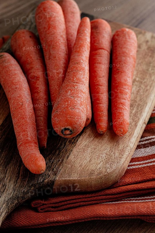 Fresh carrots on a chopping board, wooden table, raw carrots, no people
