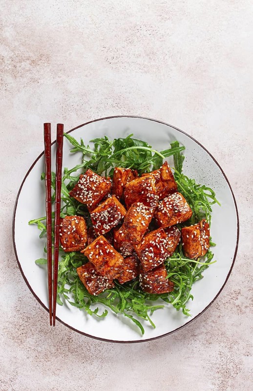 Fried salmon slices, teriyaki with sesame seeds, with arugula salad, top view