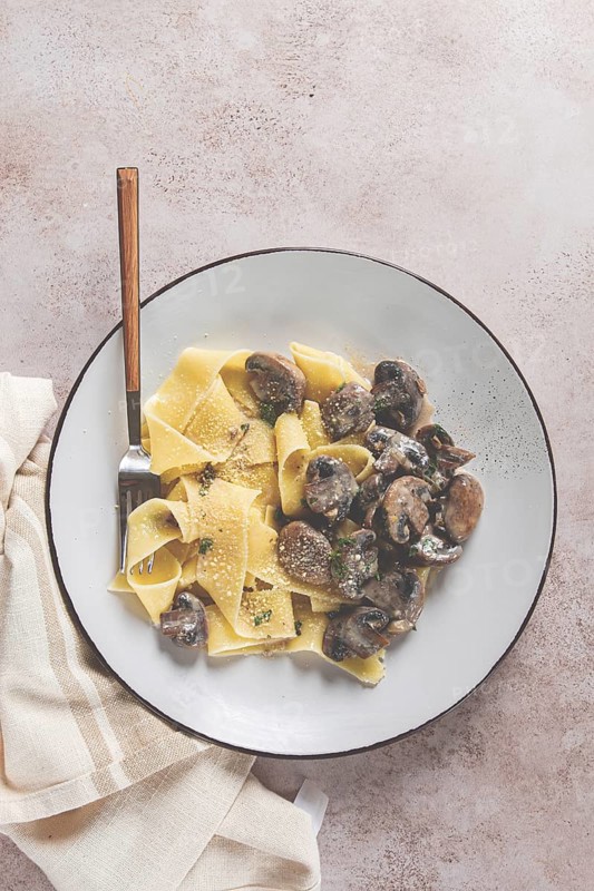 Delicious pappardelle pasta with mushrooms and cream served on a white plate