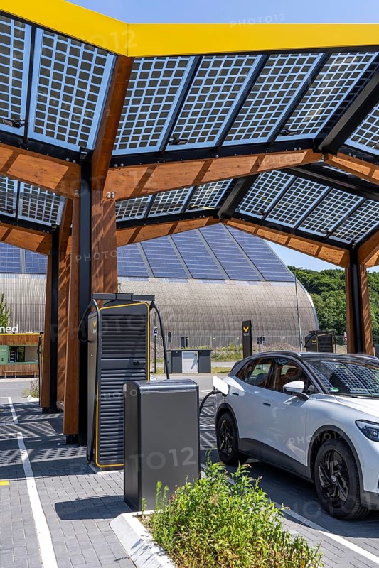 Electric charging station on the site of the former Lohberg colliery in Dinslaken, operated by Fastned, uses electricity from wind power and solar energy, fast-charging columns, with its own solar roof, in the background the 11, 500 square metre solar roof on the colliery's former coal mixing hall, North Rhine-Westphalia, Germany
