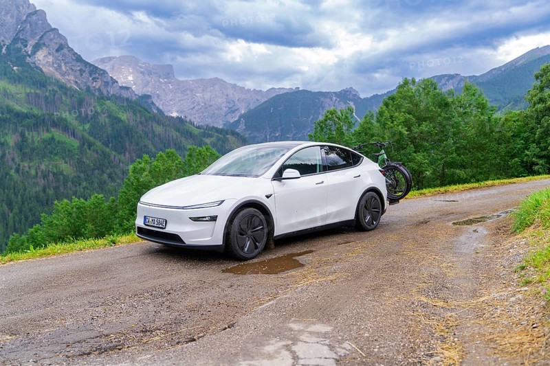 White car with bicycles on a winding mountain road, surrounded by dense greenery and cloudy sky, electric car on holiday, Dolomites, South Tyrol, Dolomites, Italy