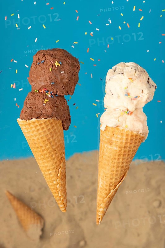 Two ice cream cones, one with chocolate ice cream and one with cream ice cream, against a blue background with sprinkles
