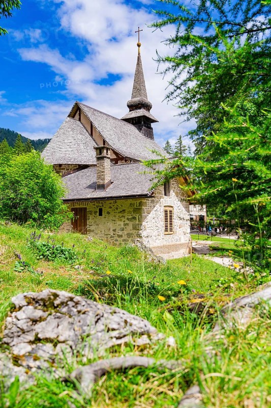Stone church with characteristic tower in a green, sunlit landscape, Lake Braies, South Tyrol, Dolomites, Italy