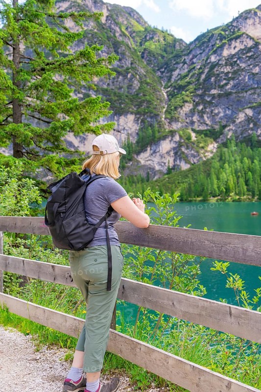 Person looking from a wooden fence at a mountain lake, surrounded by nature, Lake Braies, South Tyrol, Dolomites, Italy