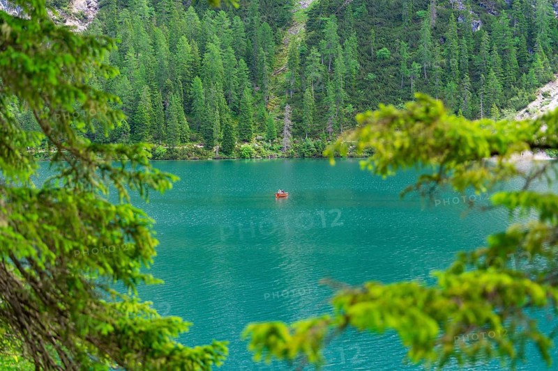 A single boat on a calm turquoise-blue lake, framed by green trees, Pragser Wildsee, South Tyrol, Dolomites, Italy