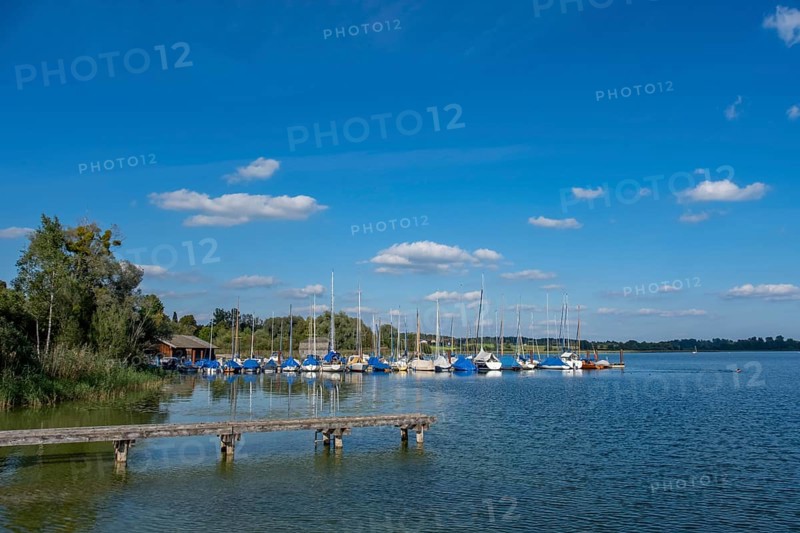 Peaceful scenery with sailing boats at the jetty and blue sky, Chiemsee, Bavaria, Germany