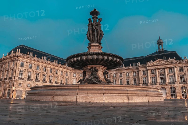 The fountain of the three graces graces place de la bourse in bordeaux, france, illuminated by the soft glow of twilight