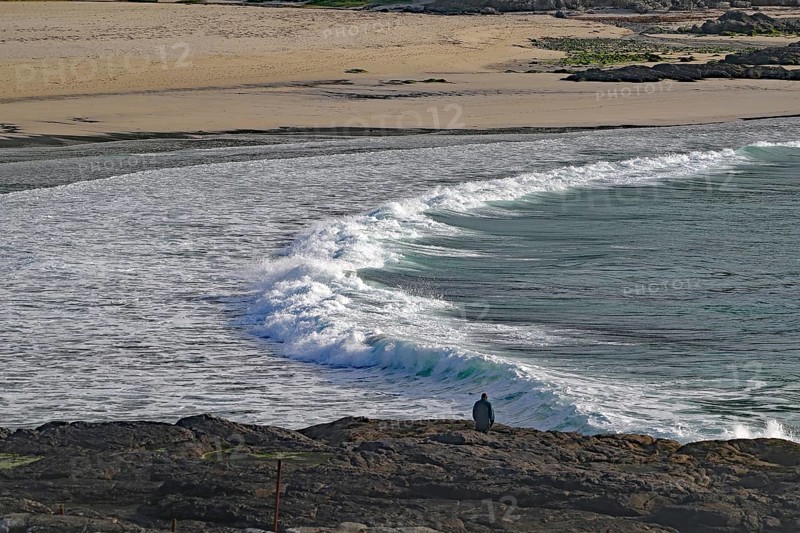 Rocky coast with crashing waves and lonely viewer under cloudy sky, Castlebay, Isle of Barra, Hebrides, Scotland, Great Britain