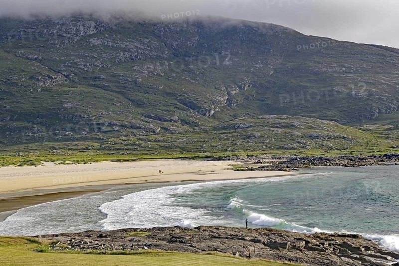 Expansive coastline with beach and waves against a mountain backdrop under a cloudy sky, Castlebay, Isle of Barra, Hebrides, Scotland, United Kingdom