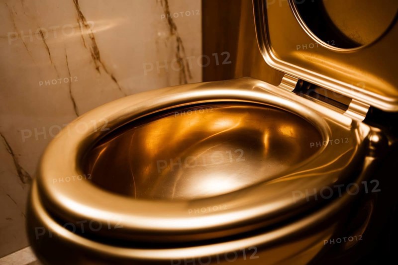 Luxurious glden toilet bowl against marble tiles. Concept for excessive decadent wealth. Generative AI, AI generated