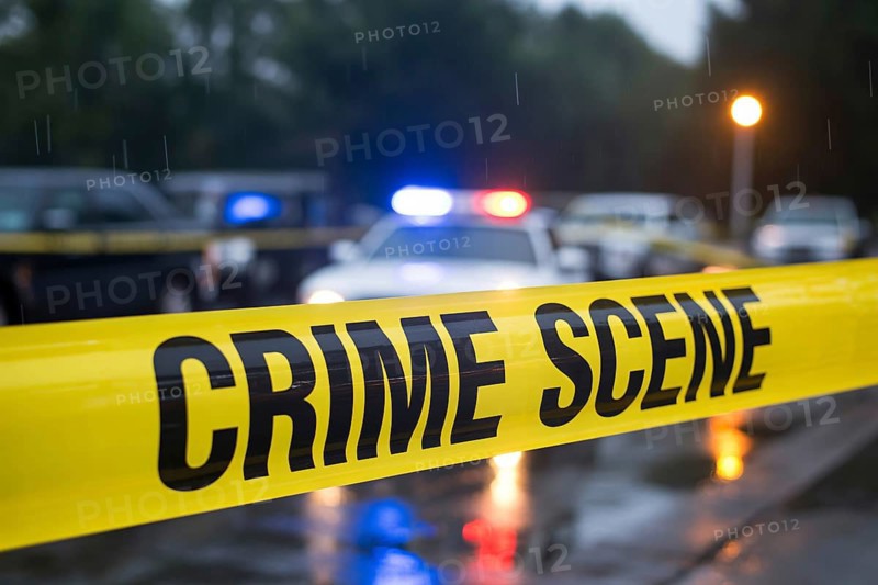 Close up of yellow crime scene tape with water droplets stretches across a rainy street with police car in blurry background. Generative ai, AI generated