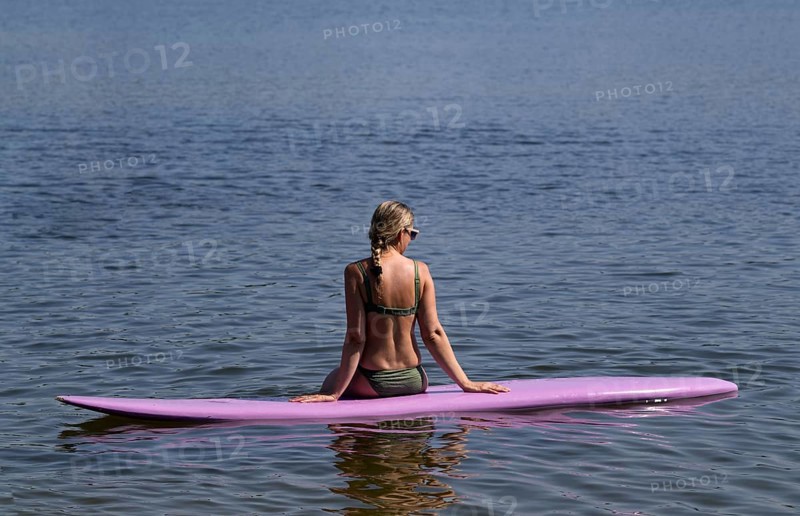 Woman, blonde, in bikini, sitting on board, surfboard, surfboard, purple, back, from behind, relaxed, bathing lake, lake, Schwaltenweiher near Seeg, Ostallgäu, Allgäu, Swabia, Bavaria, Germany