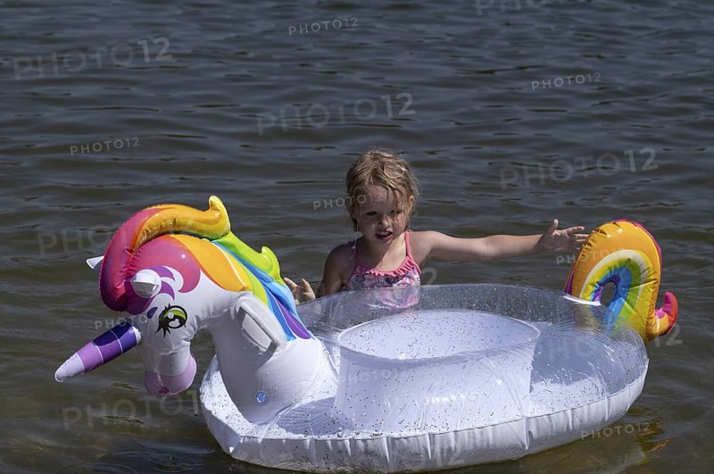 Girl, 3 years, blonde, playing with unicorn, swimming ring, inflatable, in the water, bathing lake, lake, Schwaltenweiher near Seeg, Ostallgäu, Allgäu, Swabia, Bavaria, Germany