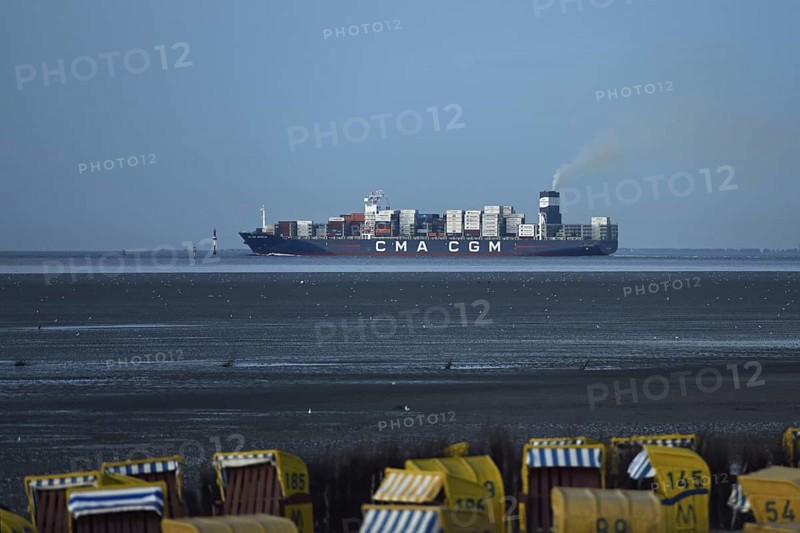 Large container ship... Elbe fairway through the Wadden Sea of the North Sea off Cuxhaven, view from Duhnen to the mouth of the Elbe, Lower Saxony, Germany, Western Europe. In the foreground you can see beach chairs where people want to enjoy their holidays