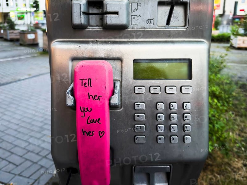 Telephone receiver of a Telekom payphone with the inscription Tell her you love her in Wuppertal, Germany