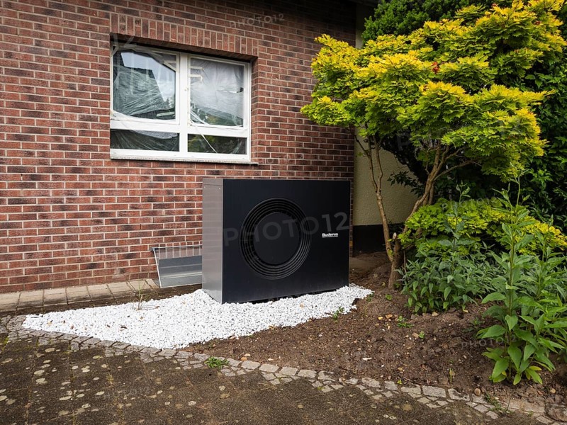 A black heat pump in a front garden in Hilden, Germany