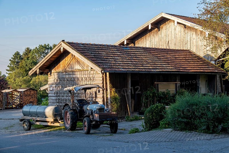 Rural scene with a wooden house and a tractor in the evening light, surrounded by nature, Bavaria, Germany