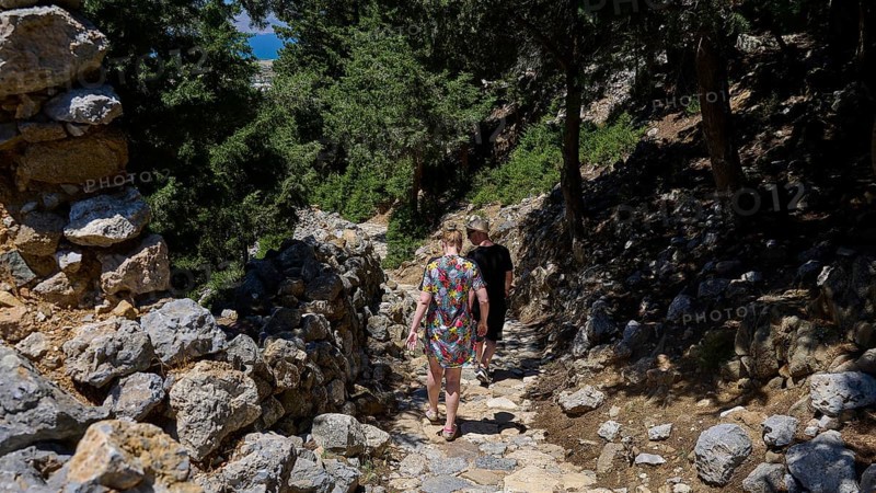 Two people walking on a stony path through a forest on a sunny day, Abandoned Village, Lost Place, Pyli, Paleo Pyli, Byzantine Fortress, Kos, Dodecanese, Greek Islands, Greece