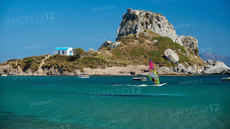 Island with windsurfer and chapel, surrounded by turquoise water, Agios Stefanos Beach, Agios Stefanos Basilica, Chapel of Agios Nikolaos, Kastri Island, Kos, Dodecanese, Greek Islands, Greece