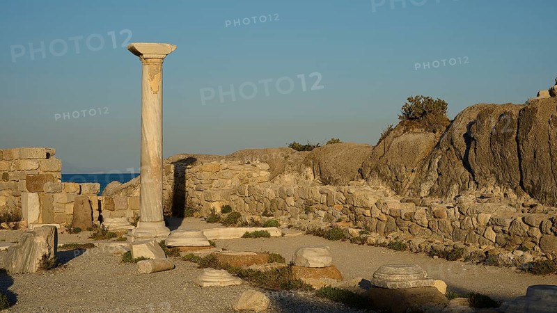 Ancient ruins with a standing stone column and surrounding rock structures in warm sunlight, Agios Stefanos Beach, Agios Stefanos Basilica, Agios Nikolaos Chapel, Kastri Island, Kos, Dodecanese, Greek Islands, Greece