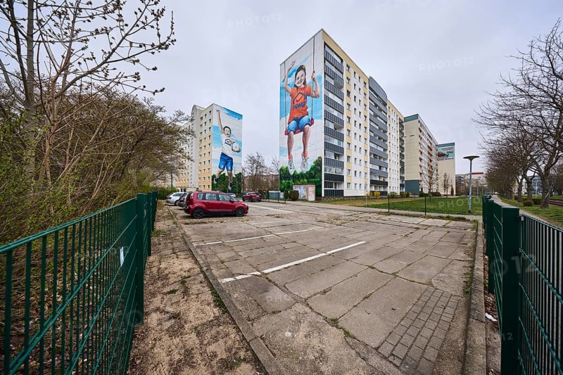 MWG-Wohnungsgenossenschaft eG Magdeburg, residential buildings, high-rise buildings, residential silos, car park, concrete slab road surface, metal fence, lantern, vehicles, diffuse light, cloudy, Lumumbastrasse, Magdeburg, state capital, independent city, Saxony-Anhalt, Germany