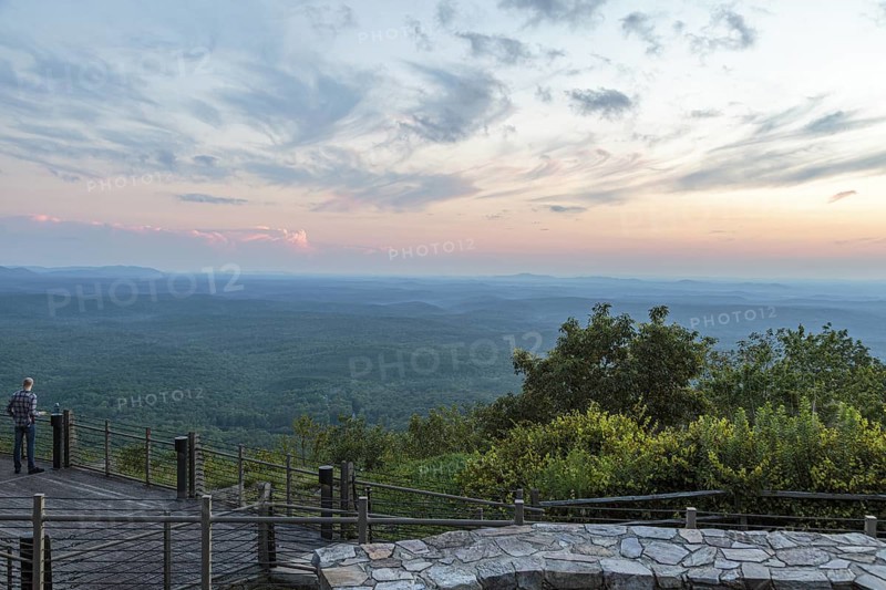 Man looking out over the valley at sunset from the Vista Cliffside Restaurant in Cheaha State Park near Delta, Alabama