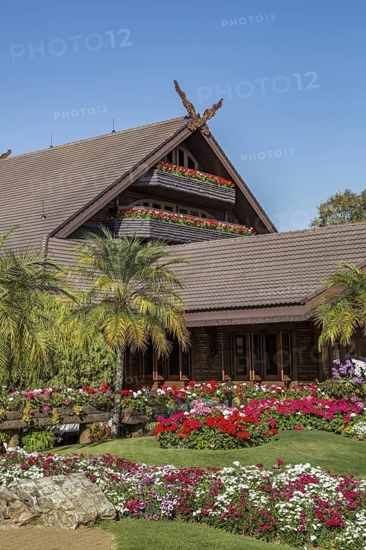 Ornate trees and lush flower gardens enhance the Lanna and Swiss architecture of the Doi Tung Royal Villa inside the Doi Tung tourist attraction in Chiang Rai, Thailand