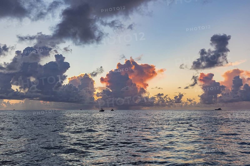 Colorful storm clouds behind the silhouette of offshore fishing boats in the Gulf of Mexico just before sunset