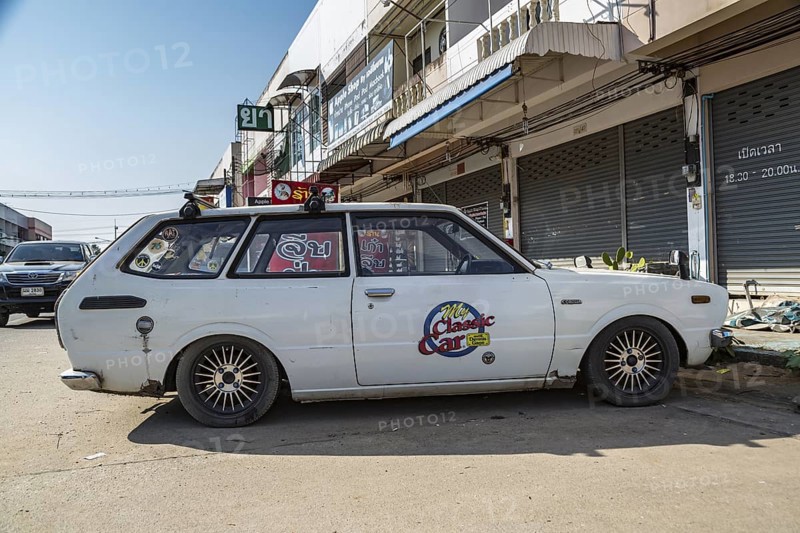 Classic 1976 Toyota Corolla station wagon with My Classic Car with Dennis Gage television program logo on door in urban area of Chiang Rai, Thailand
