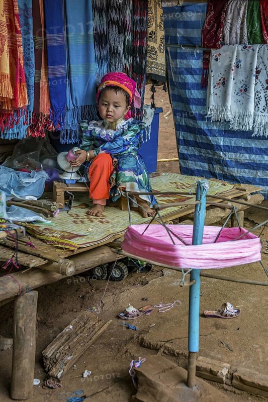 Tribal child spooling yarn for weaving scarves to be sold in the Long Neck Karen tribe (more properly called the Kayah Lahwi tribe) area of the Union of Hill Tribe Villages outside of Chiang Rai in the Nanglae District of Thailand