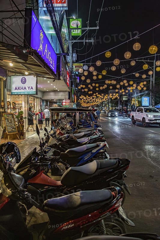 Motor scooters line the side of the downtown street in Chiang Rai, Thailand