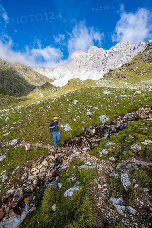 Mountaineers on a hiking trail, behind them rocky mountain peaks of the Moarer Weißen, Seven Lakes Hike, Stubai Alps, near Ridnaun, South Tyrol, Italy